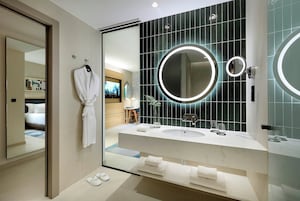 Un baño moderno con un espejo grande, dos lavamanos y una bata colgada en la pared.