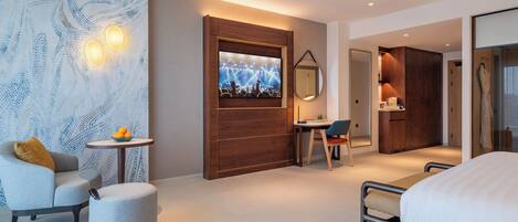 A modern hotel room with a bed, a seating area with a small table, a large mirror, and a wall with a light pattern.