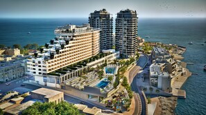A high-rise hotel with multiple balconies, a swimming pool, and a view of the sea. - Hard Rock Hotel Malta (St. Julian's)