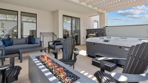 Een moderne buitenruimte met een vuurplaats, zitgelegenheid en een jacuzzi.