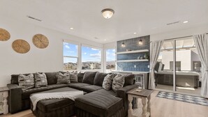 Een moderne woonkamer met een hoekbank, een bijzettafeltje en uitzicht op de stad.
