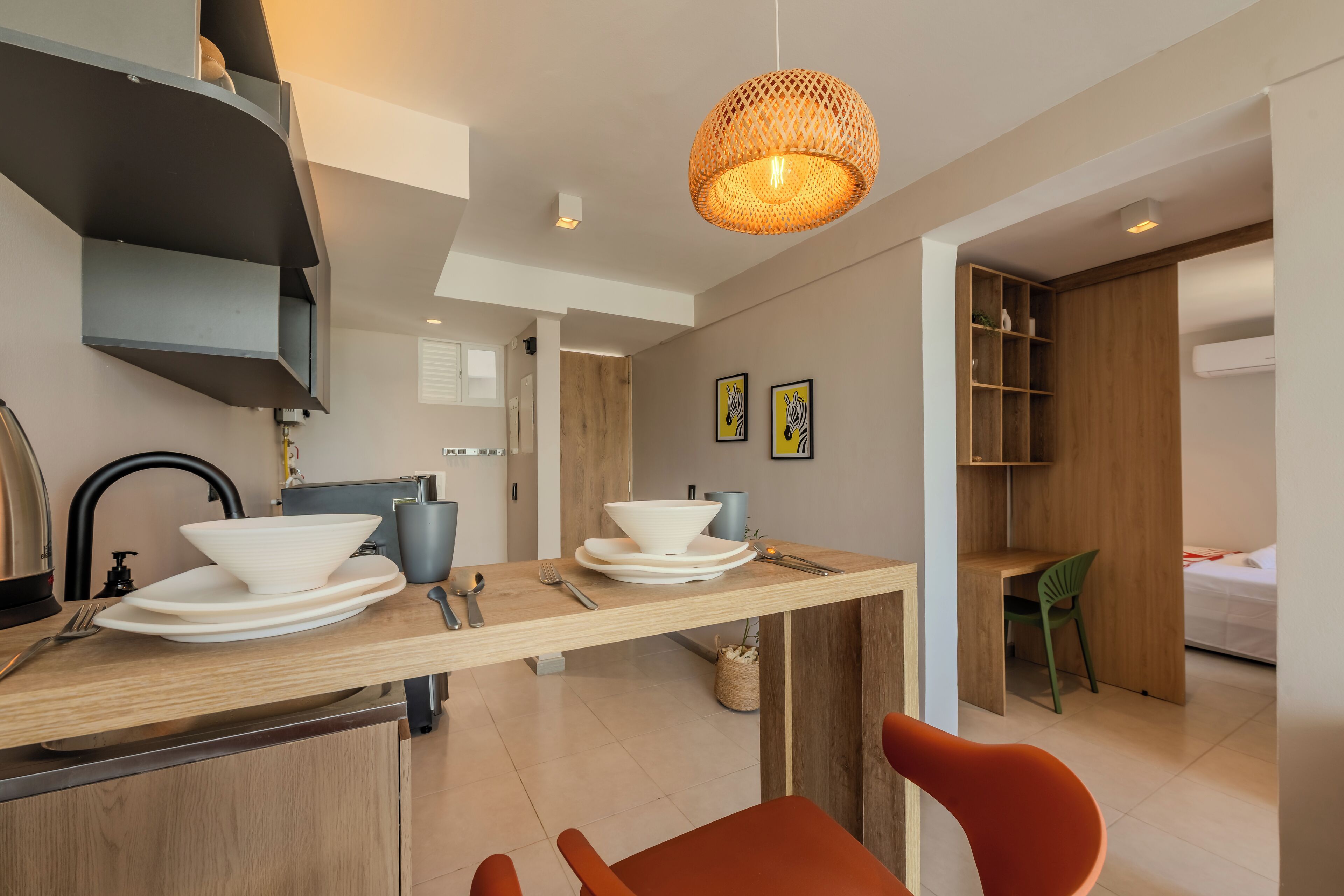 A modern kitchen with a wooden countertop, a hanging light fixture, and a dining area with a chair.