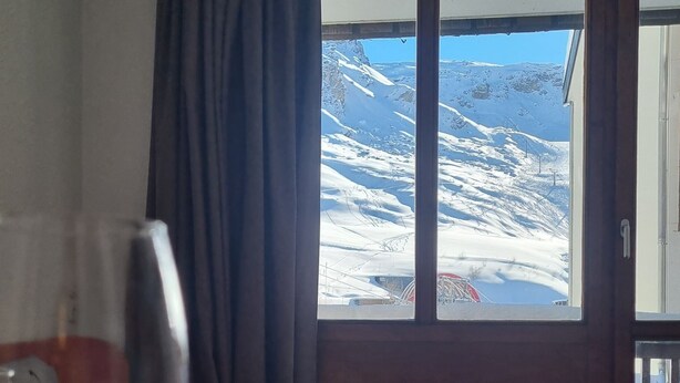Een eettafel met uitzicht op een besneeuwd berglandschap door een raam.