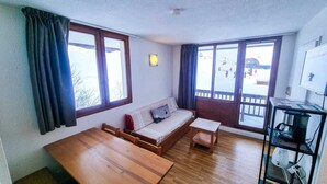 Een kamer met een houten tafel, een bank en een televisie op een standaard.