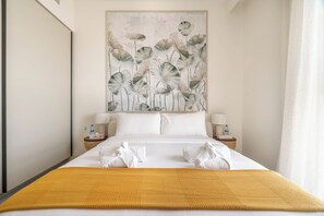 A hotel room with a bed, two bedside tables, a large floral artwork above the bed, and a yellow throw blanket. - Luxury Penthouse Retreat - Private Beach, Breathtaking Palm and Marina Views (Dubai Marina)