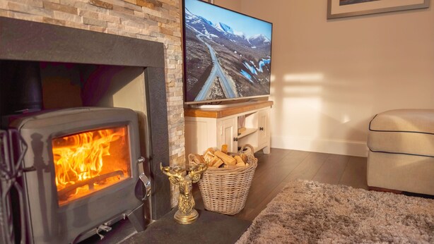 Tunnelmallinen olohuone, jossa on takka, televisio ja mukava sohva.
