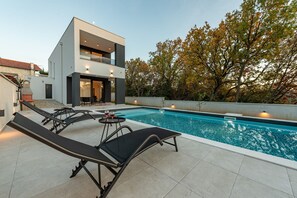 A modern two-story house with a swimming pool, lounge chairs, and a table with a glass of wine. - Villa The Family Zadarvillas (Jasenice)