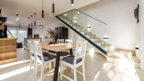 A modern kitchen with a wooden dining table, white chairs, and pendant lighting. - Villa The Family Zadarvillas (Jasenice)
