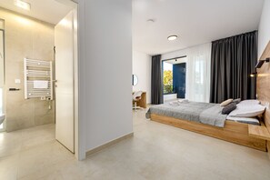 Ein modernes Schlafzimmer mit einem großen Bett, einem Schreibtisch und einer Dusche.