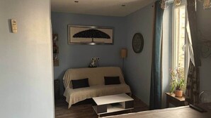 Une pièce confortable avec un canapé, une table basse et une lampe fixée au mur.