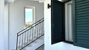 Una escalera con barandilla metálica que lleva a una puerta con ventana.