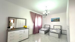 Un dormitorio con dos camas, un tocador, un espejo, una araña y un cuadro en la pared.
