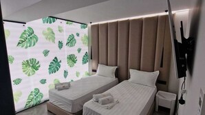 A modern hotel room with two beds, a large window with a leaf pattern, and a wooden herringbone floor. - Tirana Room Rentals • Twin Room • Free Wi-Fi • Private Bathroom • Flat-Screen TV (Tirana)