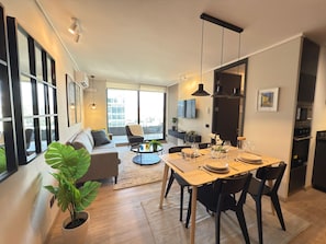 A modern living room with a sofa, coffee table, and dining table set up for a meal. - HOM | De LUJO 2D2B 4PAX cerca a Mall AltoLasCondes (Las Condes)