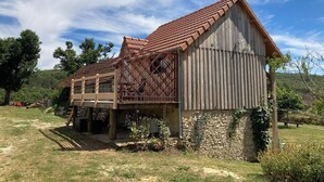 A rustic wooden building with a sloped roof and a wooden deck. - Le PERCHOIR, comfortable gîte (Bouzic)