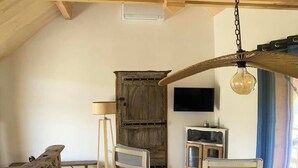 A rustic wooden dining area with a high ceiling, a wooden table with placemats, and a television mounted on the wall. - Le PERCHOIR, comfortable gîte (Bouzic)