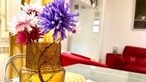 En vas i två våningar, tillverkad av glas, med blommor på ett glasbord.