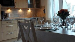 A kitchen with wooden cabinets, a microwave, and a dining area with a table set for two. - Apartment 4 with Balcony and Wi-Fi (Horumersiel)