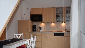 A compact kitchen with wooden cabinets, a microwave, a coffee maker, and a dishwasher. - Apartment 4 with Balcony and Wi-Fi (Horumersiel)
