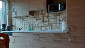 A kitchen with wooden cabinets, a microwave, a tiled backsplash, a sink, and a coffee maker. - Apartment 'Ferienwohnung 3' with Balcony and Wi-Fi (Horumersiel)