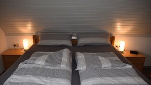 A double bed with a striped bedspread, two bedside tables with lamps, and a wooden headboard.
