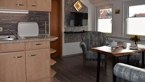 A modern kitchen with wooden cabinets, a built-in microwave, and a stone backsplash.