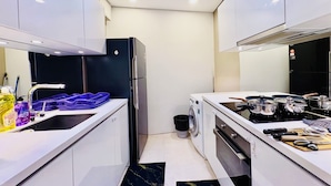 Una cocina moderna con armarios blancos, un refrigerador negro, una lavadora y una estufa.
