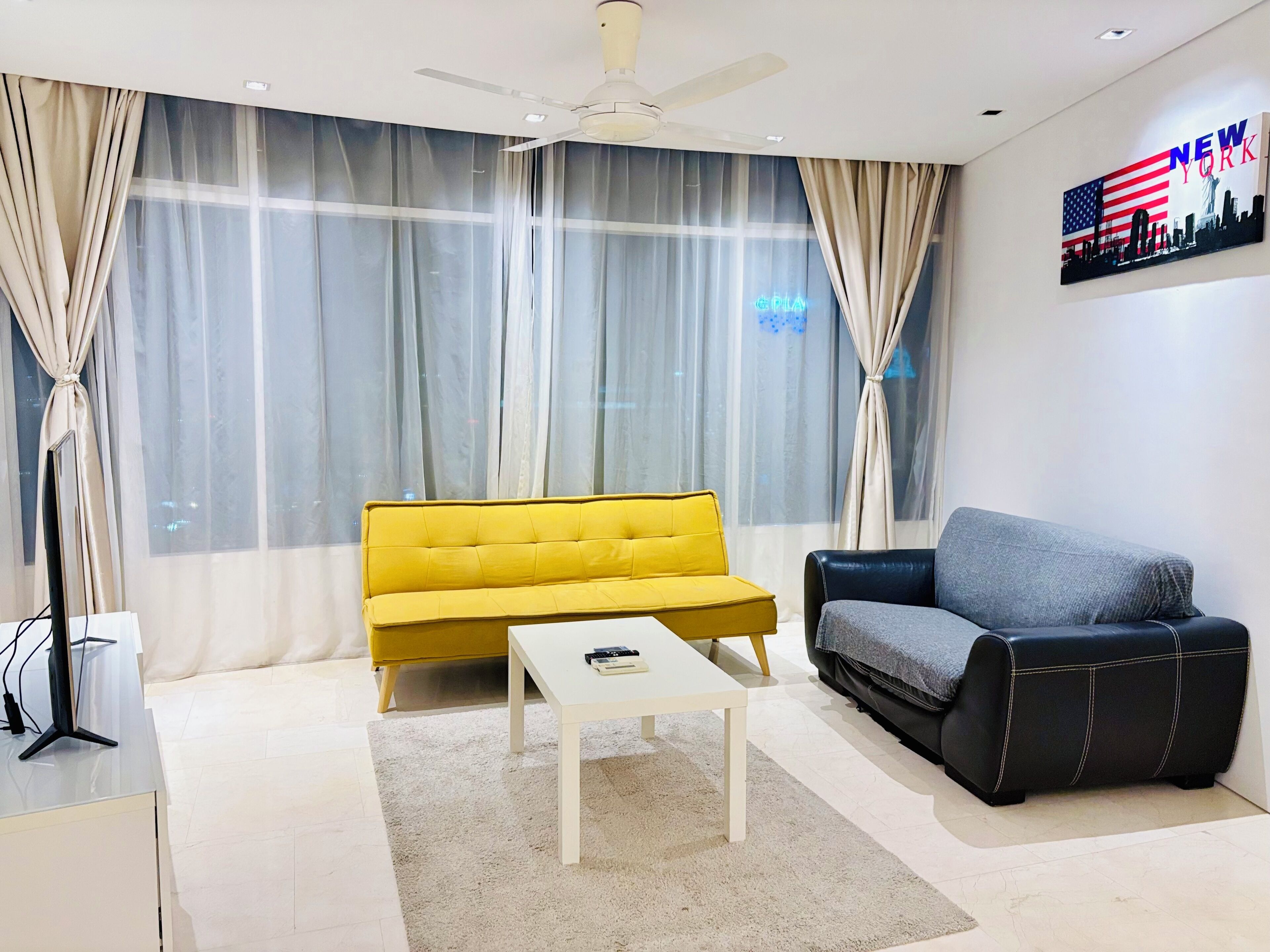 Una sala de estar moderna con un sofá amarillo, una mesa de centro blanca y un sofá de cuero negro.