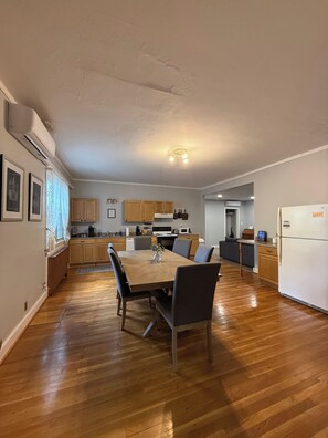 A modern kitchen with wooden cabinets, a dining table with chairs, and a refrigerator.