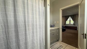A bathroom with a shower curtain, a sink with a towel, and a radiator.