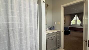 A bathroom with a shower curtain, a sink, and a mirror.