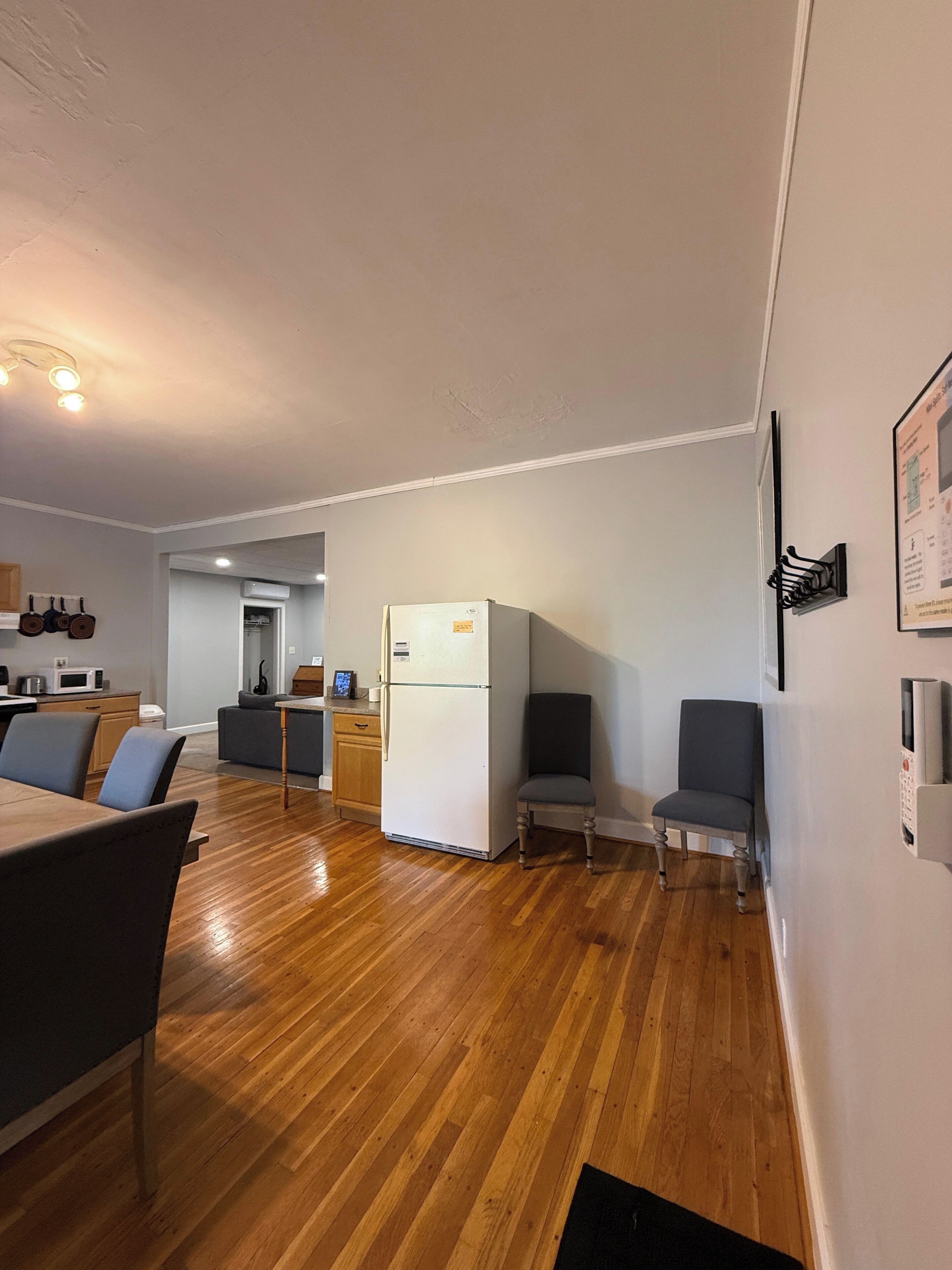 Una cocina moderna con refrigerador, piso de madera y un área de comedor con sillas.