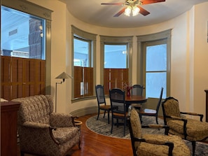 A room with a curved ceiling, wooden shutters, a dining table with chairs, and a patterned armchair. - NH4:Timeless Elegance 1BR Haven in Historic Home (DuBois)