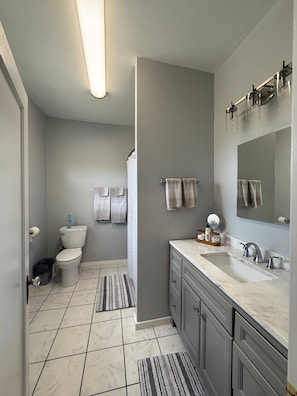 A bathroom with a toilet, sink, mirror, and towel rack. - NH4:Timeless Elegance 1BR Haven in Historic Home (DuBois)