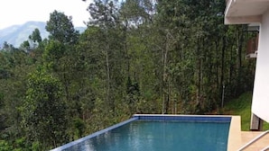 Ein rechteckiger Infinity-Pool mit gefliestem Rand, umgeben von einer Holzterrasse.