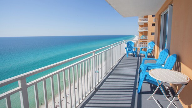 Un balcone con vista sull'oceano, sedie blu e un tavolino.