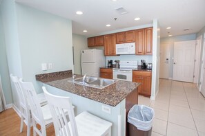 A modern kitchen with granite countertops, white cabinetry, and stainless steel appliances. - Splash Resort 1701E - B • Beachfront 2BR • Sleeps 8 • Pools & Waterpark (Panama City Beach)