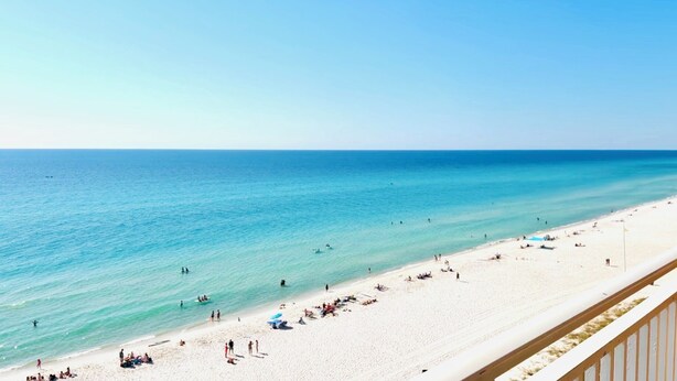 Ein Strand mit klarem türkisblauem Wasser, weißem Sand und einigen Sonnenanhenden.