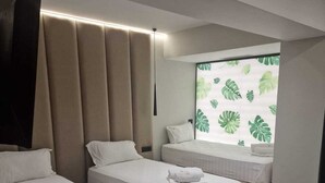 A hotel room with two beds, a large window with a plant pattern, and a modern design.