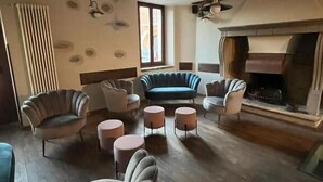 Amplia sala de estar con chimenea, varios lugares para sentarse y un techo alto.