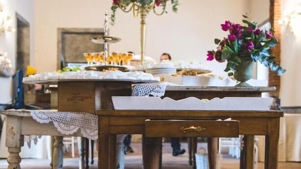 Una mesa de madera rústica con un centro de mesa floral, un candelabro y un pequeño jarrón con flores.