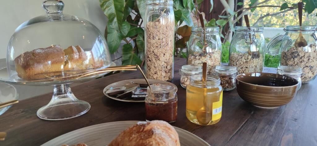 A table with a loaf of bread, jars of honey, and a bowl of oatmeal.