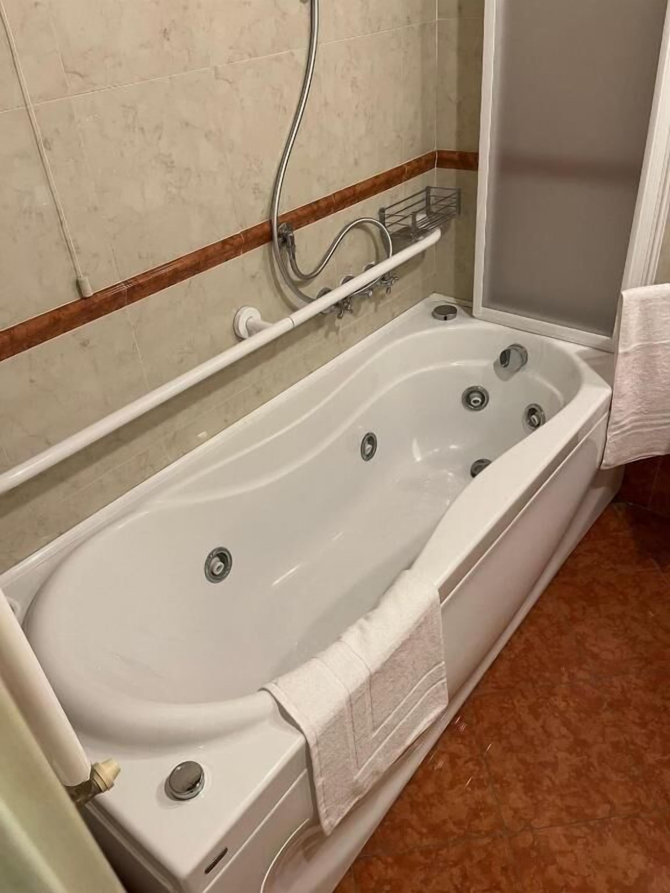 A bathroom with a bathtub, a shower, and a towel rack.