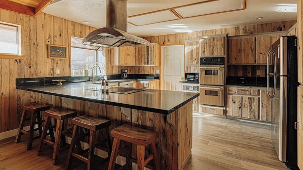 A kitchen with a large island, wooden cabinets, and stainless steel appliances. - Wildwood Chalet, 5 mins to ski resorts w/game room (Big Bear Lake)