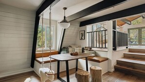 Una habitación acogedora con un banco de madera, una mesa y una lámpara colgante.
