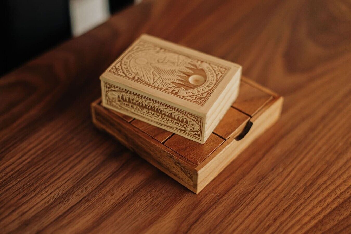 A stack of playing cards on a wooden coaster.