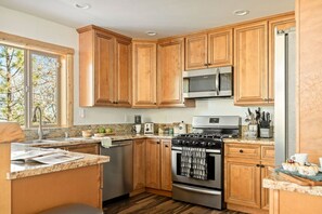 A kitchen with wooden cabinets, a stainless steel refrigerator, a microwave, a stove, and a dishwasher. - Oak Tree Lodge, w/ Hot Tub, Fire Pit, Game Room (Big Bear)