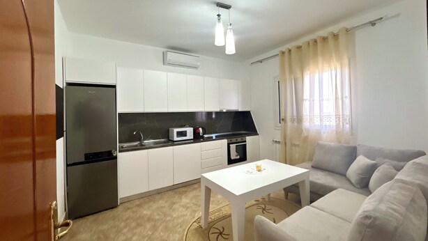 Een knus woongedeelte met een kitchenette, een bank en een eettafeltje.
