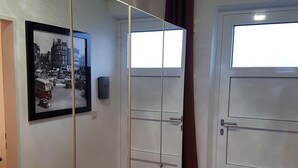 A hallway with a framed black and white photo on the wall, a door with a window, and a door with a handle. - Apartment 'Meerblick' with Sea View, Balcony and Wi-Fi (Horumersiel-Schillig)
