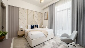 Une chambre moderne avec un grand lit, des tables de chevet, une chaise et un lustre.